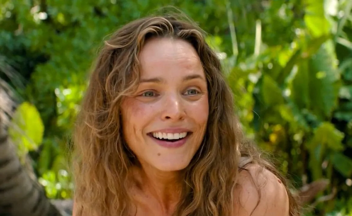 A smiling woman with tousled hair against tropical foliage in Send Help.
