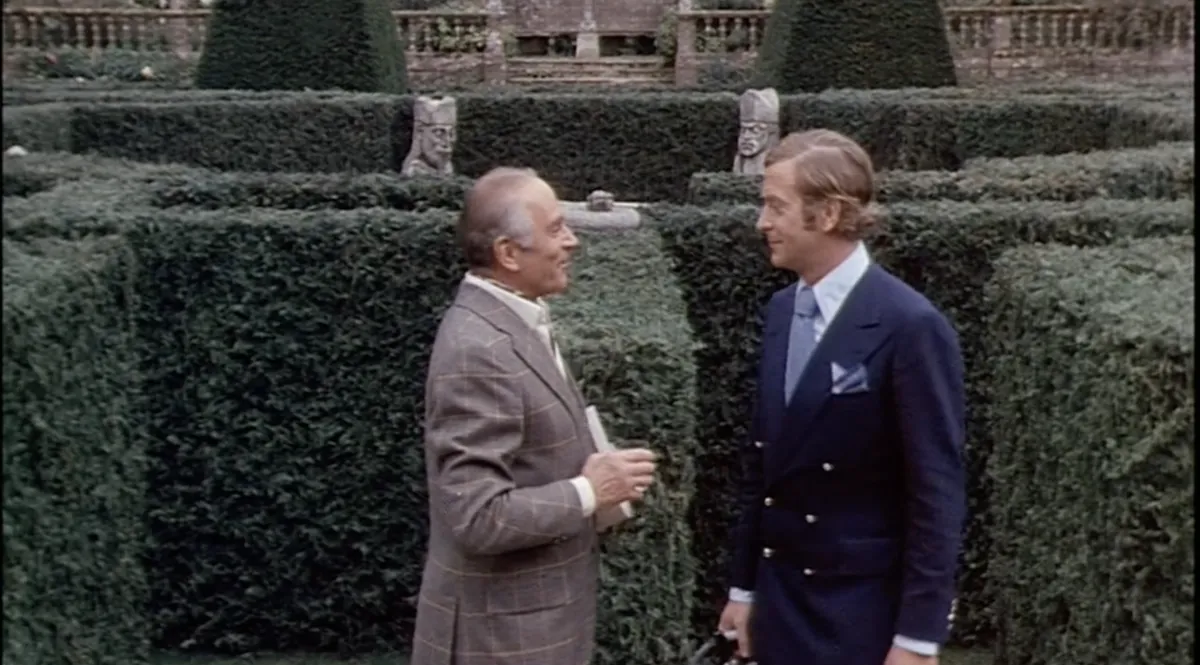 Laurence Olivier and Michael Caine converse beside a hedge maze in Sleuth (1972).